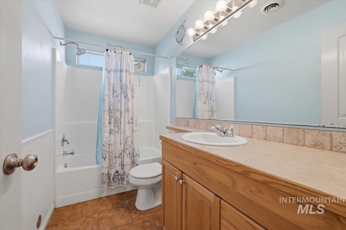1068 Locksley Street Middleton, ID 83644 - Photo 16 of 30 Bathroom featuring a wood-finish vanity with an integrated sink, a large wall-mounted mirror, and a full bathtub with an overhead shower