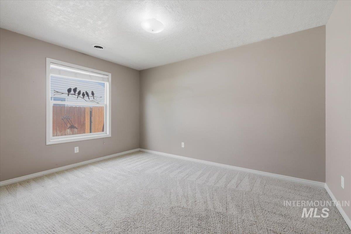 1068 Locksley Street Middleton, ID 83644 - Photo 17 of 30 Neutral-toned room featuring light-colored carpeting, a single window with white trim, and a flush-mount ceiling light fixture