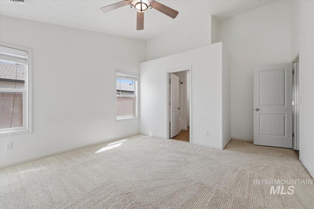 1068 Locksley Street Middleton, ID 83644 - Photo 19 of 30 Spacious room featuring vaulted ceilings, two windows with white trim, light-toned patterned carpeting, and a ceiling fan with wood-finish blades