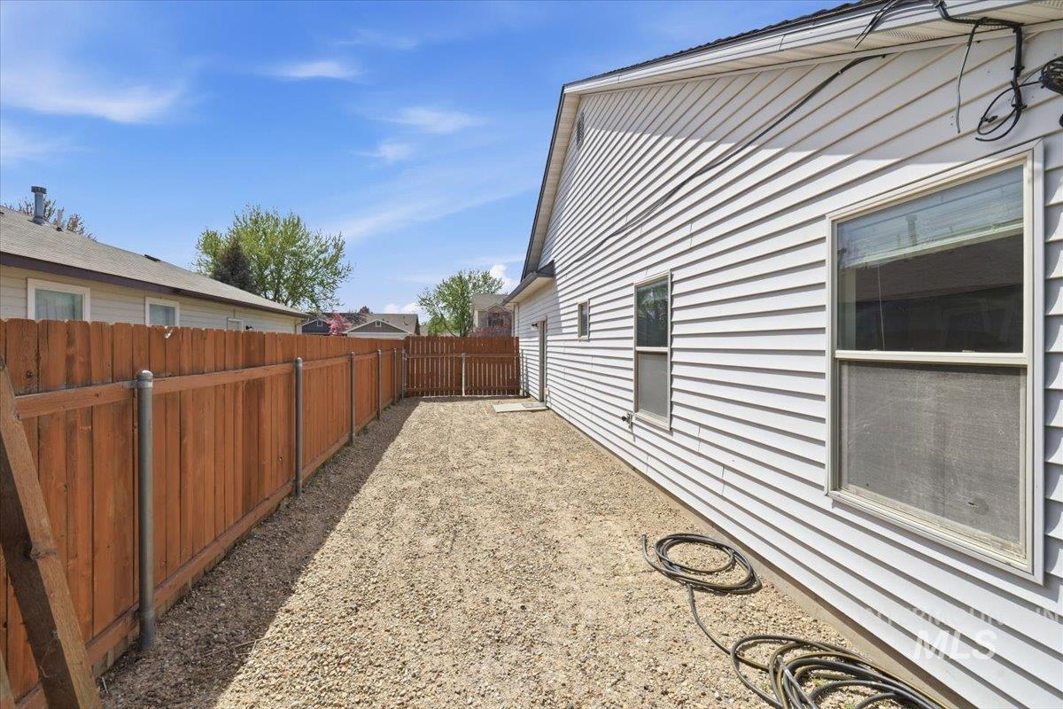 1068 Locksley Street Middleton, ID 83644 - Photo 27 of 30 Side yard featuring white siding, a wood privacy fence, and a gravel surface