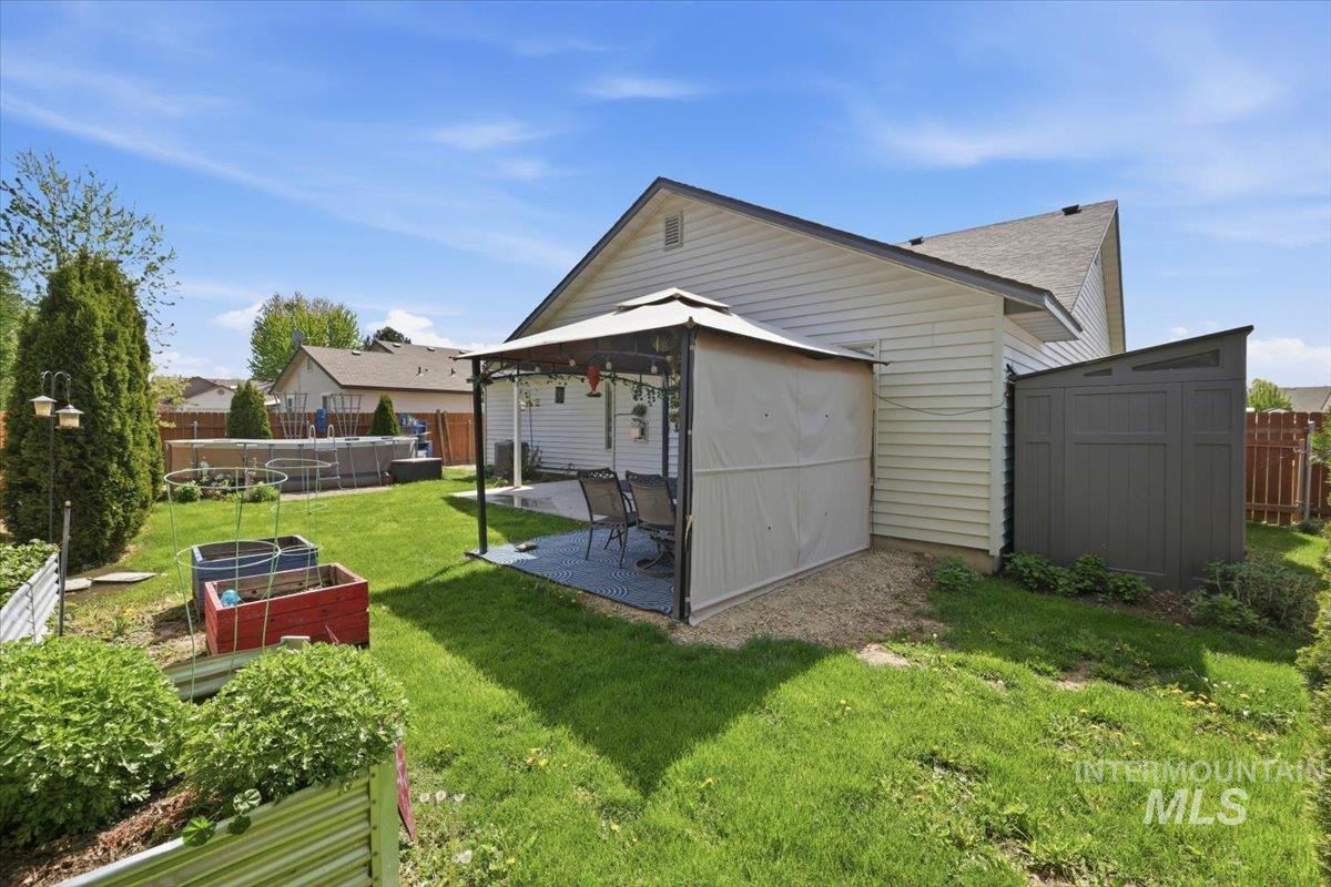 1068 Locksley Street Middleton, ID 83644 - Photo 28 of 30 Expansive backyard featuring a patio area with a pergola, a manicured lawn, and raised garden beds