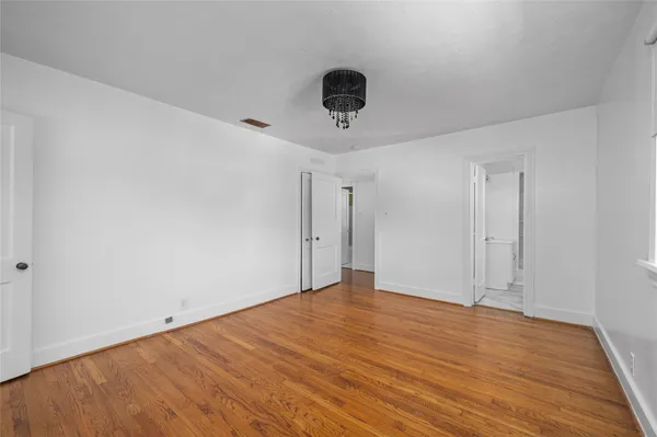 a view of an empty room with wooden floor and a ceiling fan