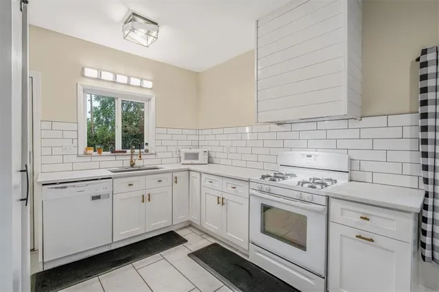 a kitchen with white cabinets stainless steel appliances and a window
