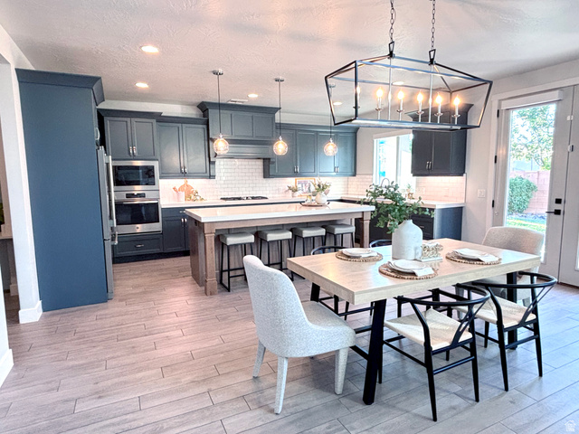 429 East Treasure Road Washington, UT 84780 - Photo 9 of 20 Spacious kitchen and dining area featuring custom cabinetry, stainless steel appliances, a center island with bar seating, and wood-finish flooring