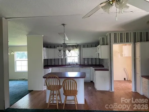 a kitchen with stainless steel appliances granite countertop a dining table chairs refrigerator and sink