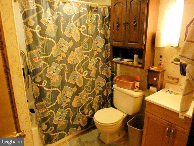 304 Miles Road Baltimore, MD 21221 - Photo 7 of 19 a bathroom with a toilet and a shower curtain