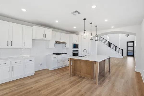 a large kitchen with cabinets wooden floor and stainless steel appliances