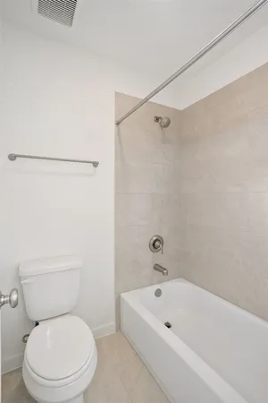a white toilet sitting next to a bath tub and a shower