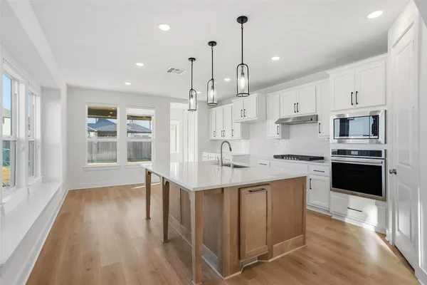 a kitchen with kitchen island a sink a stove and a window
