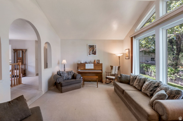 11072 Windy Peak Ridge Drive, Unit 32 Sandy, UT 84094 - Photo 12 of 30 Spacious living area featuring expansive windows with transom detailing, vaulted ceilings, and plush carpeting