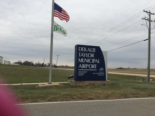 a view of a lake with lawn chairs and large trees