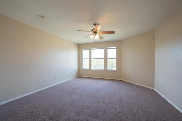 an empty room with a window and a ceiling fan