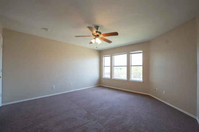 an empty room with chandelier fan and windows