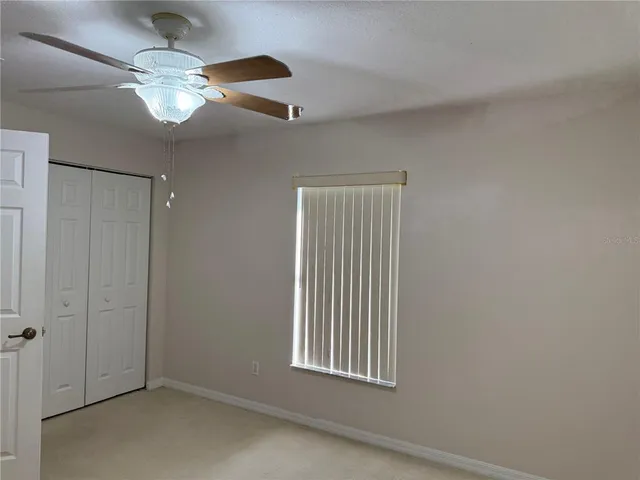 an empty room with windows and chandelier fan