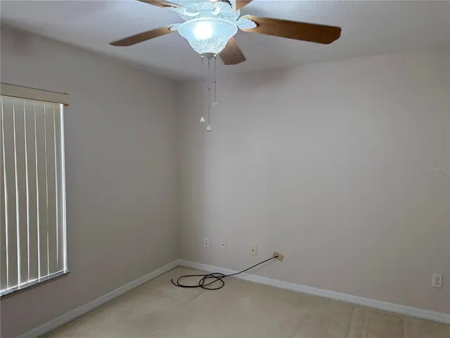 an empty room with a window and a fan