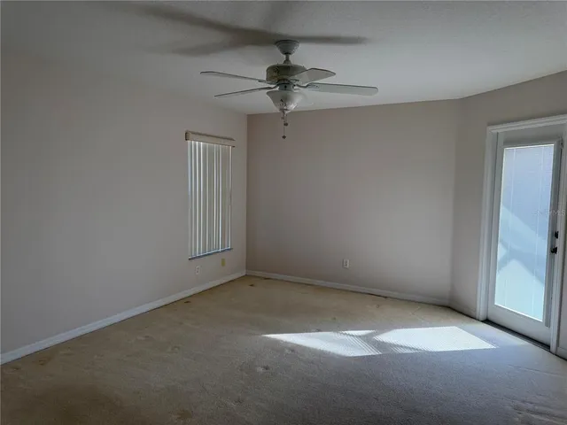 an empty room with a ceiling fan and window