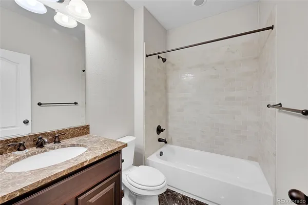 a bathroom with a granite countertop sink a toilet and shower