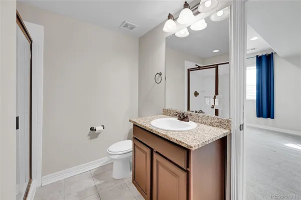 a bathroom with a granite countertop sink a toilet and a mirror