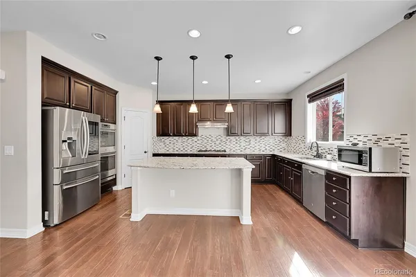 a large kitchen with stainless steel appliances and wooden cabinets