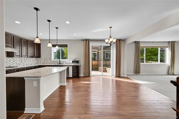 a large kitchen with granite countertop a large counter top a sink stainless steel appliances and cabinets