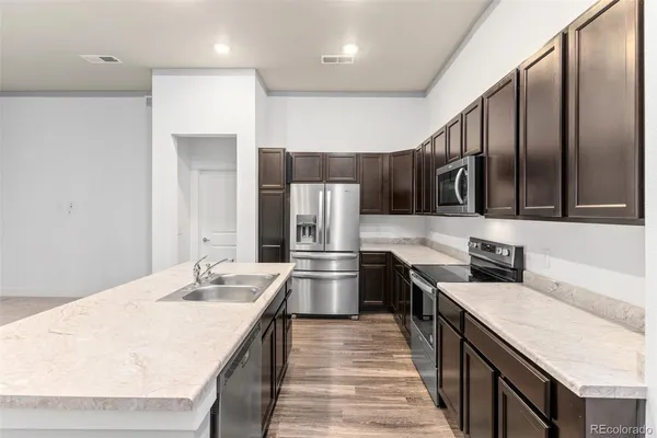 a kitchen with stainless steel appliances granite countertop a sink a stove and a refrigerator