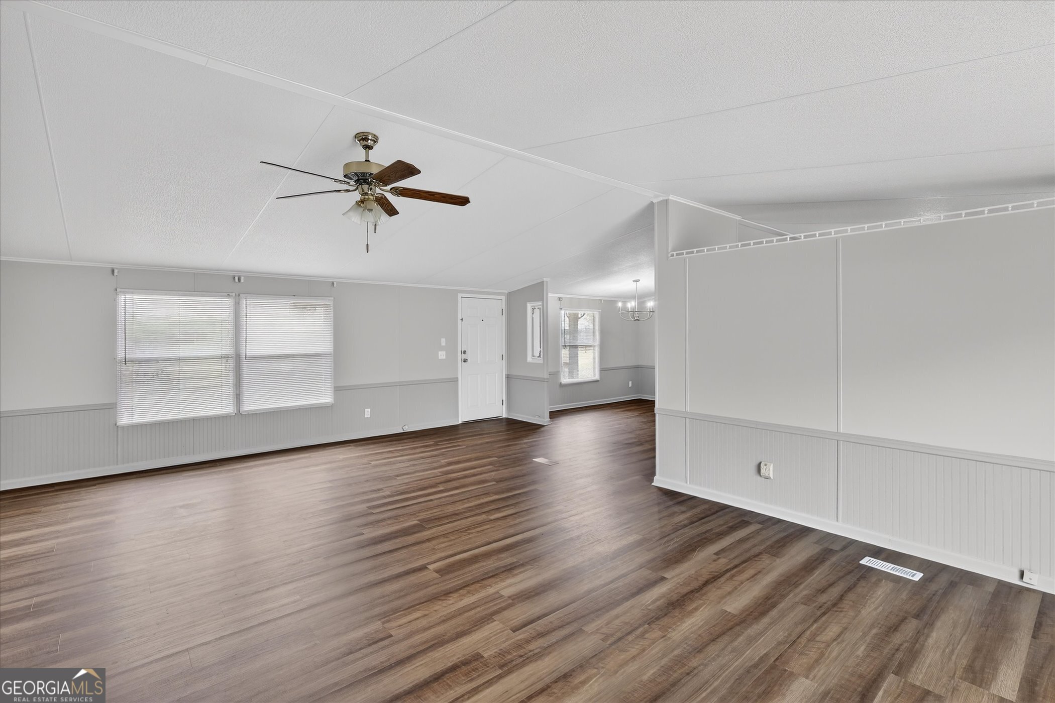 13541 Pine Burr Road Metter, GA 30439 - Photo 8 of 44 an empty room with wooden floor chandelier fan and windows