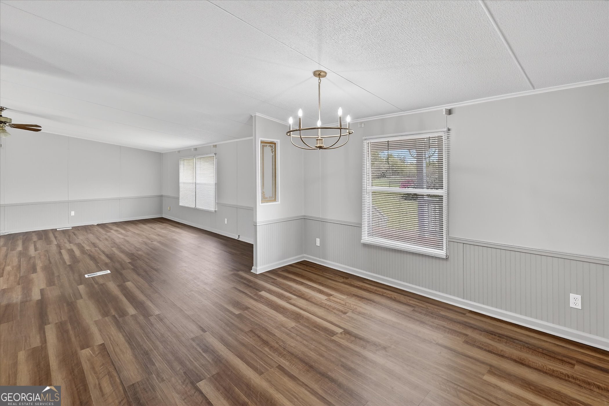 13541 Pine Burr Road Metter, GA 30439 - Photo 9 of 44 an empty room with wooden floor chandelier and windows