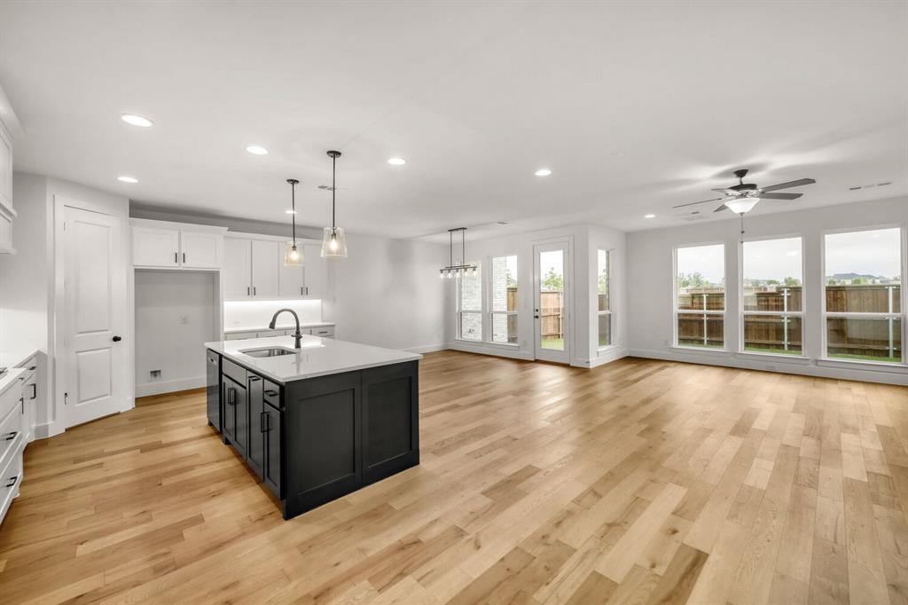 3420 Brocco Road Celina, TX 75009 - Photo 10 of 27 Open concept living space featuring wood-finish flooring, a kitchen island with sink, white shaker cabinetry, recessed lighting, and multiple windows