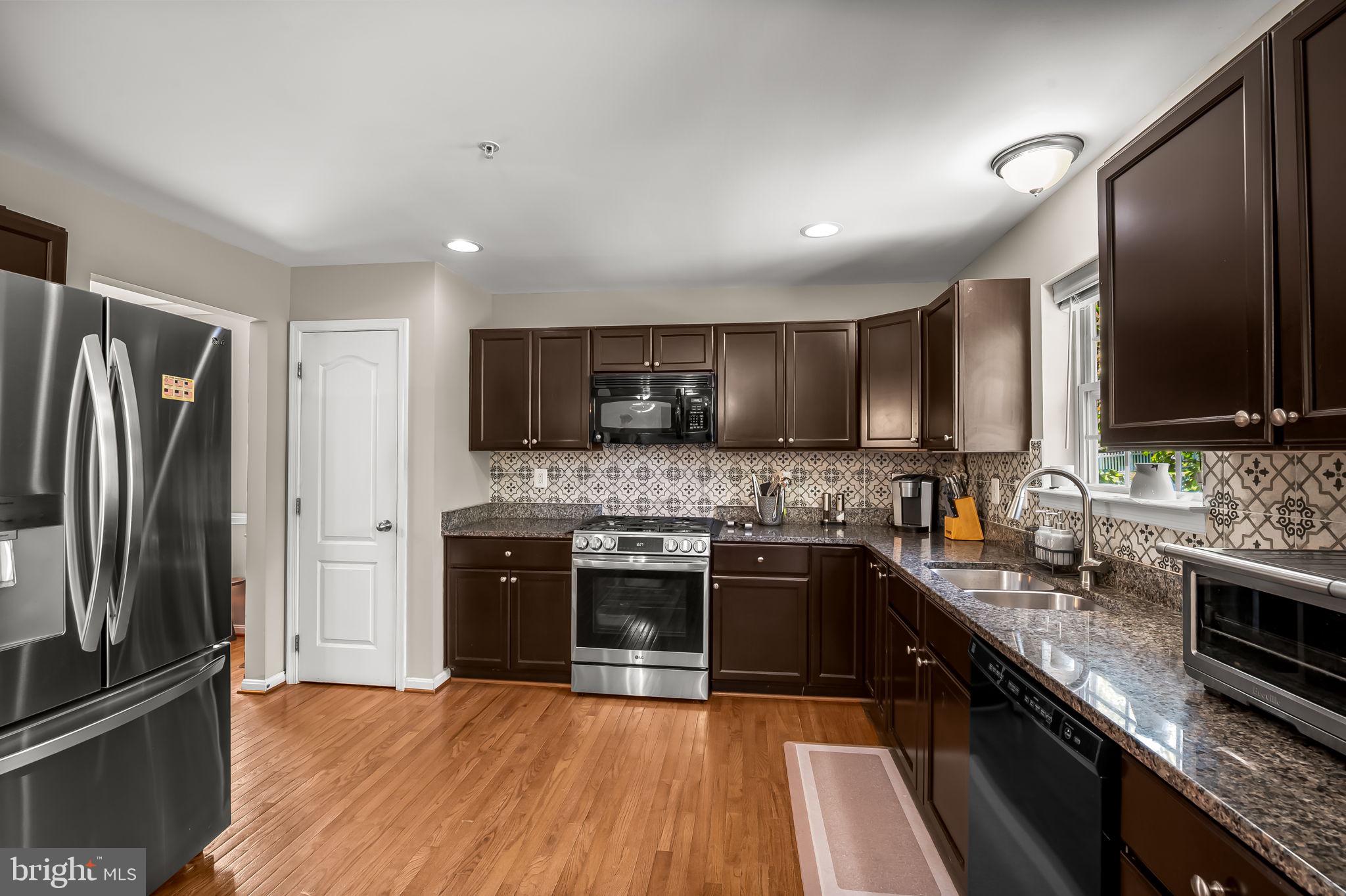 6008 Hanover Road Elkridge, MD 21075 - Photo 11 of 36 a kitchen with stainless steel appliances granite countertop a sink stove microwave and refrigerator