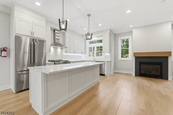 a kitchen with stainless steel appliances a stove a sink a refrigerator and a fireplace