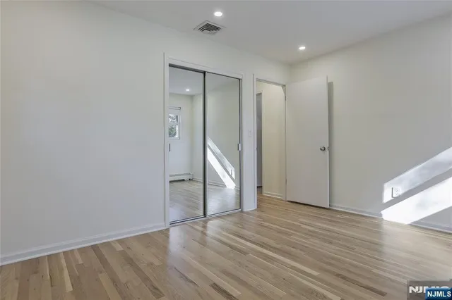 a view of an empty room with wooden floor and closet