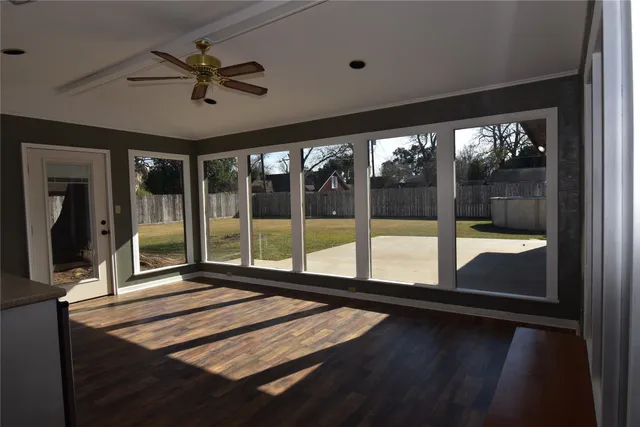 a view of an empty room with wooden floor and a window