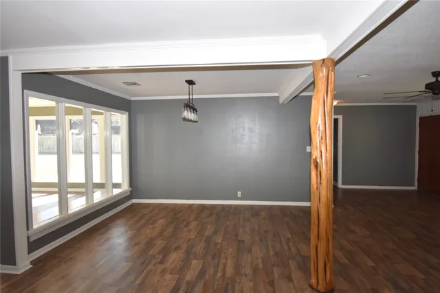 an empty room with wooden floor fireplace and windows