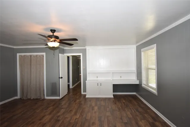 an empty room with wooden floor chandelier fan and windows