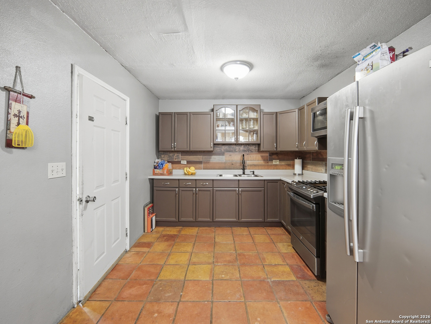 17525 Benton City Road Von Ormy, TX 78073 - Photo 9 of 36 a kitchen with a refrigerator a sink and cabinets