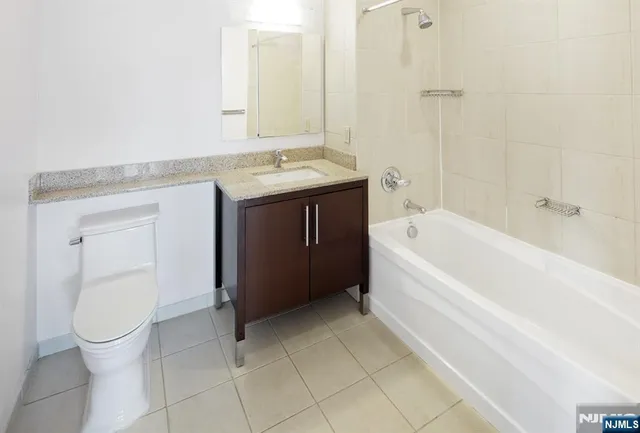 a bathroom with a granite countertop sink a toilet and bathtub