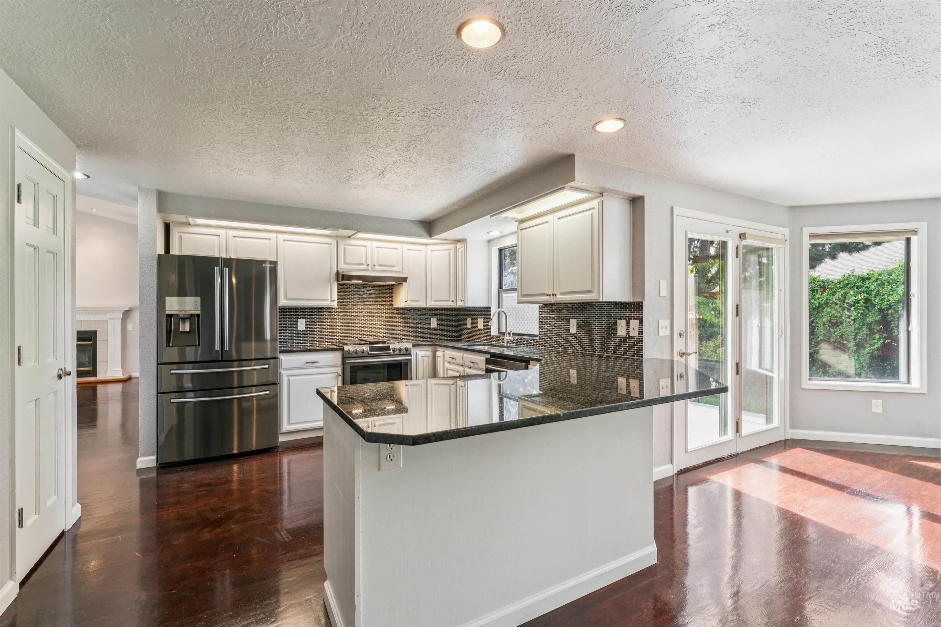 9831 West Ripley Street Boise, ID 83704 - Photo 14 of 47 Spacious interior featuring a brick fireplace with a wood mantle, rich wood-finish flooring, and a ceiling fan
