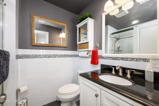a bathroom with a granite countertop toilet a sink and a mirror