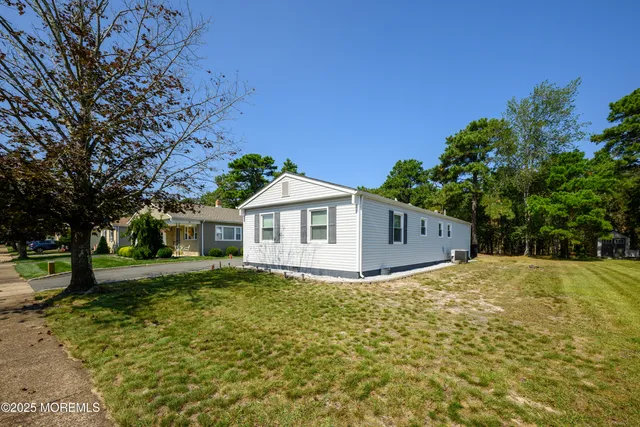 a front view of house with yard and trees in the background