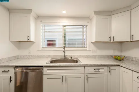 a kitchen with granite countertop white cabinets and a window