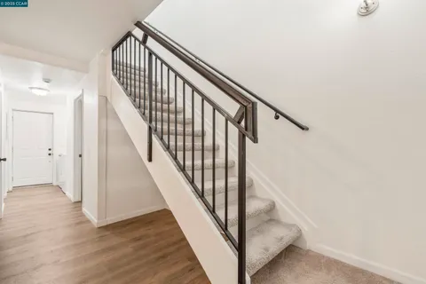 a view of staircase with wooden floor and white walls