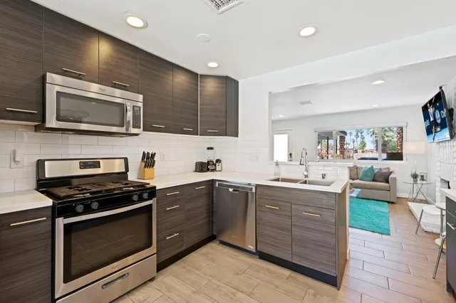 a kitchen with stainless steel appliances kitchen island granite countertop wooden cabinets stove top oven and sink