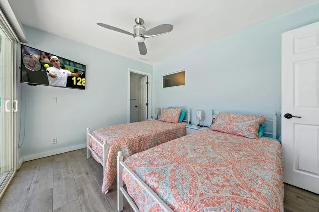 a bedroom with two beds and ceiling fan