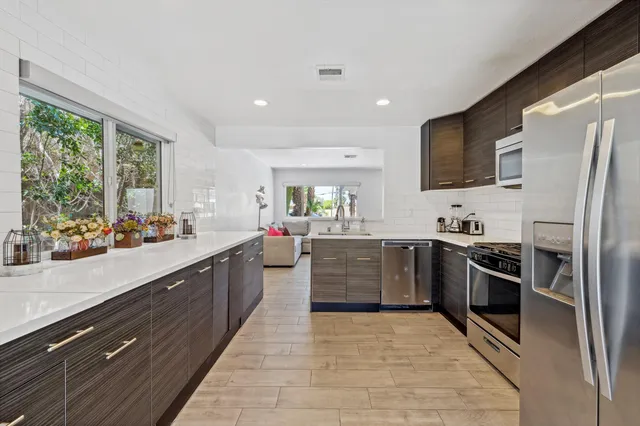 a large kitchen with a large counter top stainless steel appliances and windows