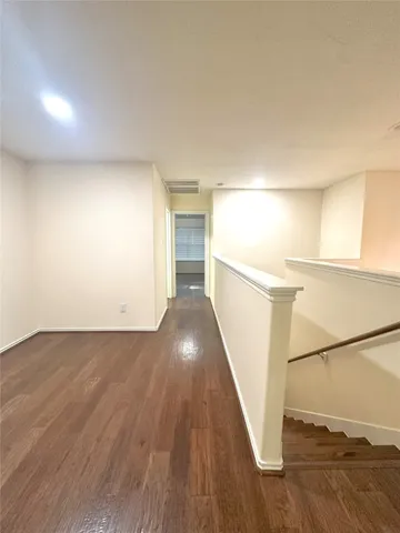 an empty room with wooden floor chandelier fan and windows