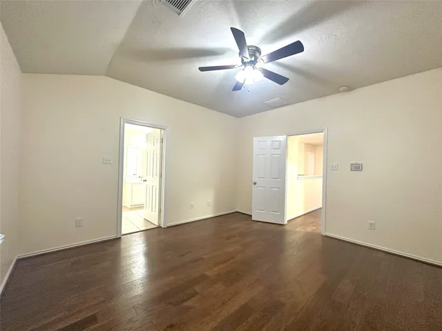 an empty room with wooden floor chandelier fan and windows