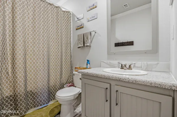 a bathroom with a granite countertop toilet sink and mirror