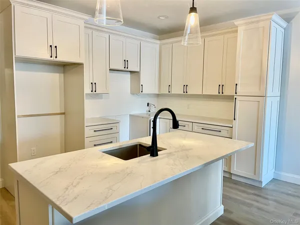 a kitchen with stainless steel appliances granite countertop a refrigerator a sink a stove and white cabinets with wooden floor