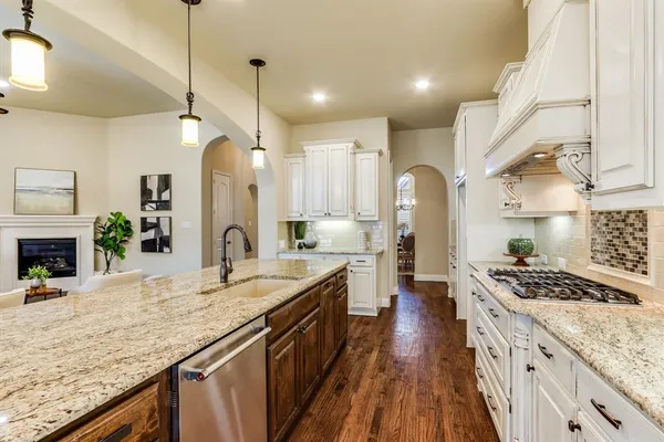 a kitchen with granite countertop a stove a sink a refrigerator and a wooden cabinets