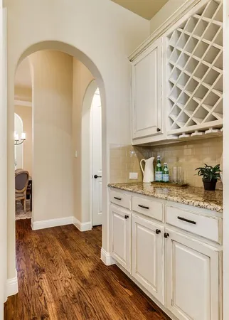 a kitchen with granite countertop white cabinets and wooden floor